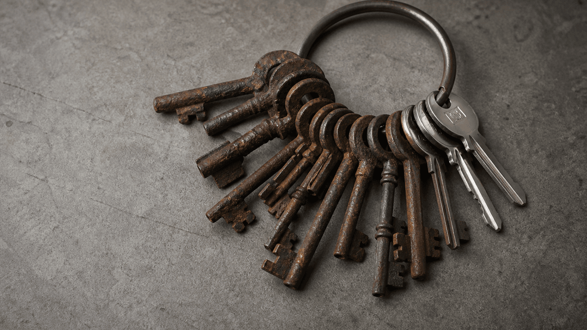 Bunch of keys on a metal ring on a stone slab, most keys rusted with broken bits, three of them bright